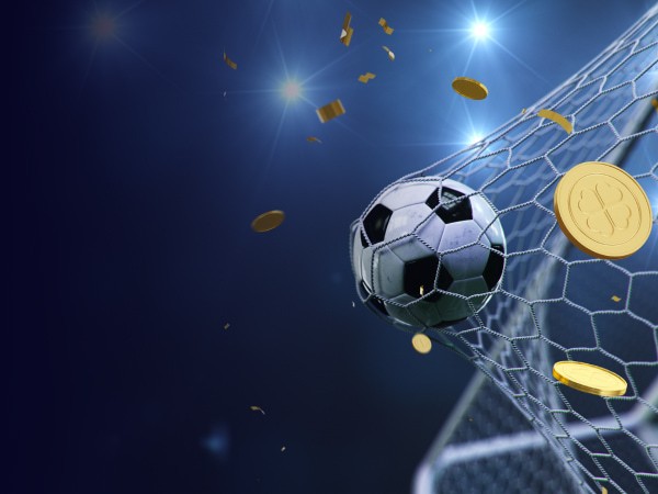 ฟุตบอลสัมผัสตาข่ายประตูหลังจากผ่านเสาประตู แสงไฟจากสนามฟุตบอลส่องให้เห็นพื้นหลังที่มืดสนิท